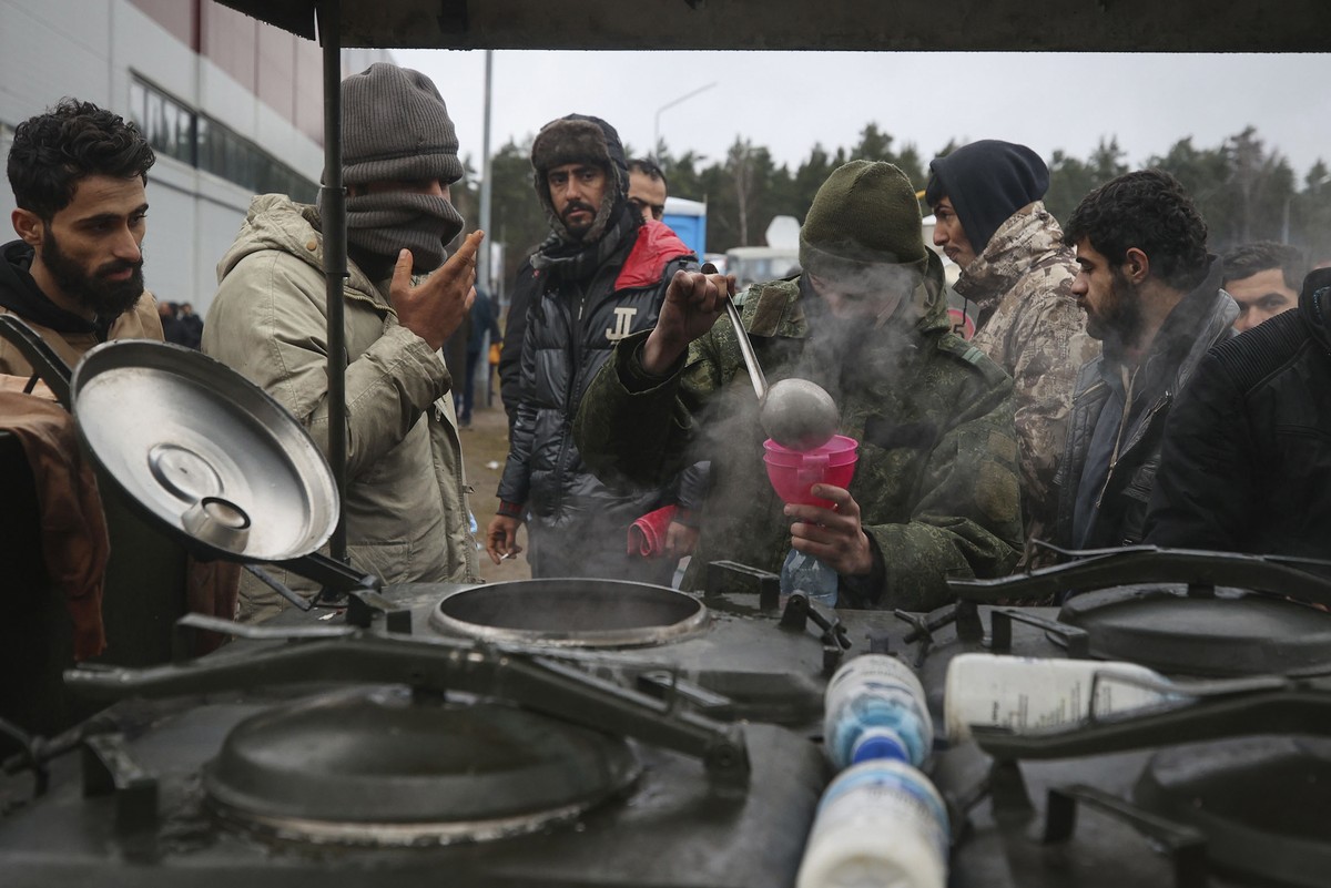 Migrants receive food delivered by Belarusian officials in the logistics center at the checkpoint "Kuznitsa" at the Belarus-Poland border near Grodno, Belarus, on Friday, Nov. 19, 2021. Hund ...