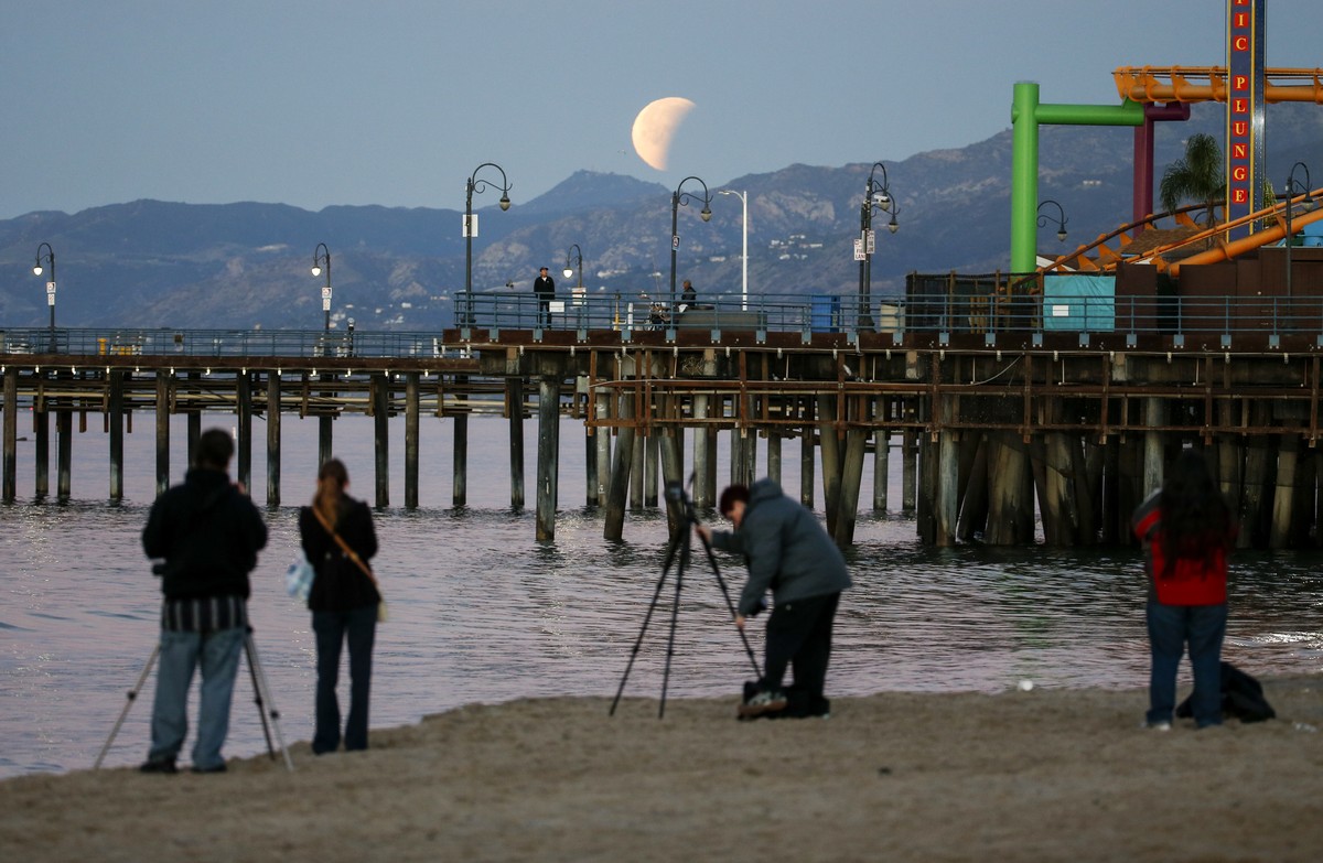 People take photos a rare occurrence called a 'Super Blue Blood Moon' at Santa Monica Beach in Santa Monica, Calif., Wednesday, Jan. 31, 2018. It's the first time in 35 years a blue moo ...