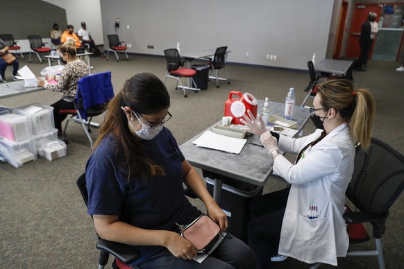 epa09472316 Student Minerva Ruiz, L, waits to receive a a dose of the Pfizer BioNTech vaccine from healthcare worker Uyen Vo (R), at a vaccination clinic at California State University, Dominguez Hill ...