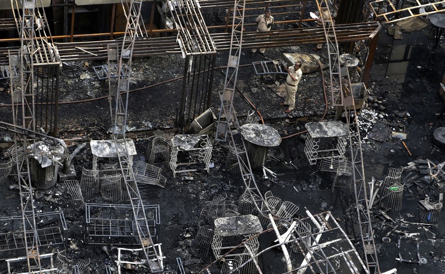 A police officer takes the photo of totally charred restaurant in Mumbai, India, Friday, Dec. 29, 2017. A number of people were killed and many more injured in a fire that broke out in a restaurant in ...