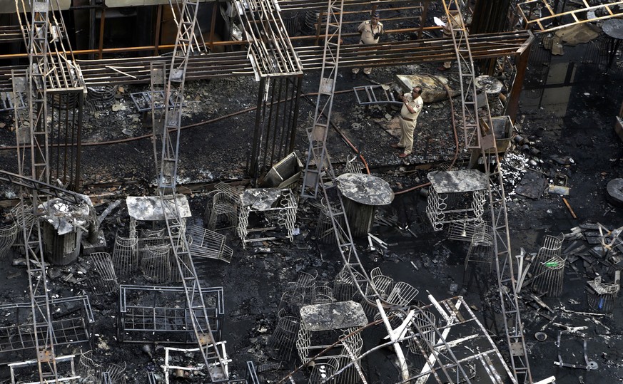 A police officer takes the photo of totally charred restaurant in Mumbai, India, Friday, Dec. 29, 2017. A number of people were killed and many more injured in a fire that broke out in a restaurant in ...