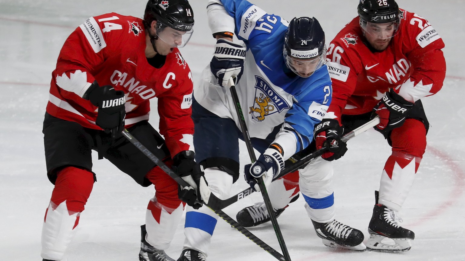 epa09240821 Hannes Bjorninen (C) of Finland in action against Canadian players Adam Henrique (L) and Sean Walker (R) during the IIHF Ice Hockey World Championship 2021 group B match between Canada and ...