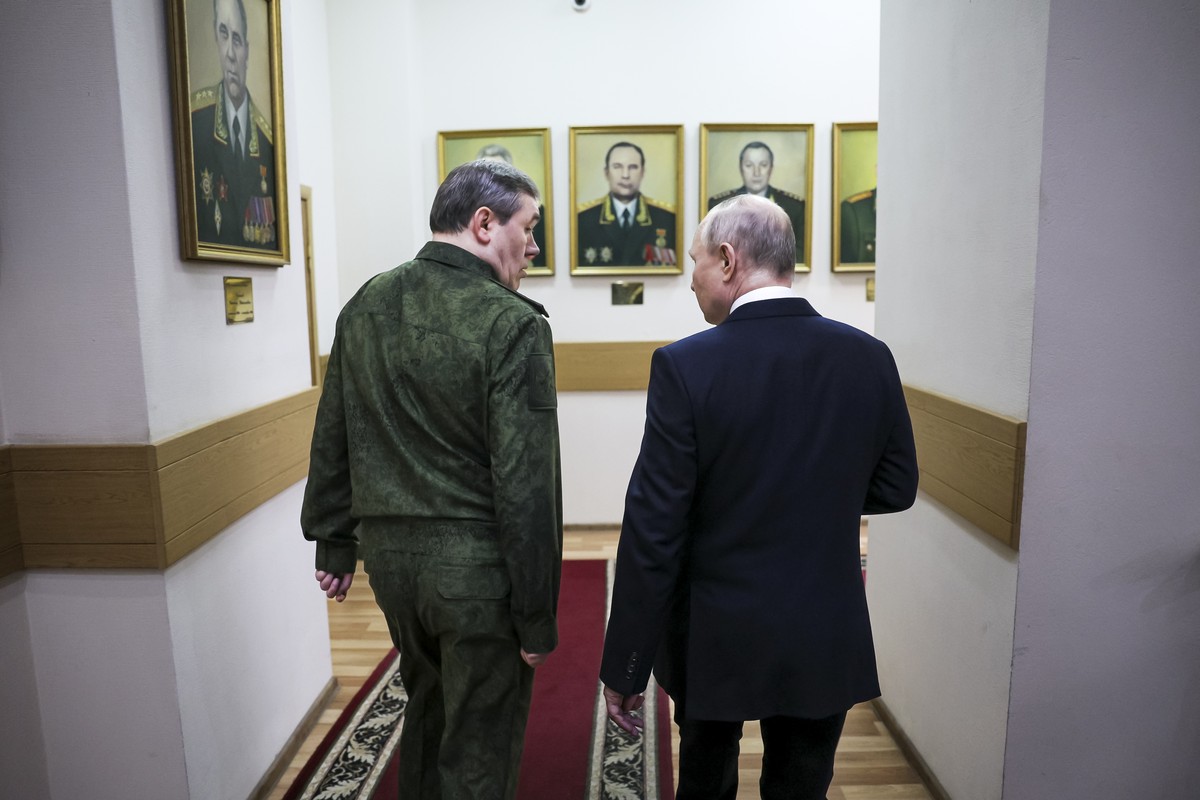 Russian President Vladimir Putin, right, and Russian Chief of General Staff Gen. Valery Gerasimov talk to each other as they walk through a corridor at the headquarters of Russia's Southern Milit ...