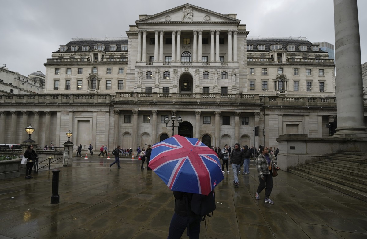 A woman with an umbrella stands in front of the Bank of England, at the financial district in London, Thursday, Nov. 3, 2022. The Bank of England has announced its biggest interest rate increase in th ...