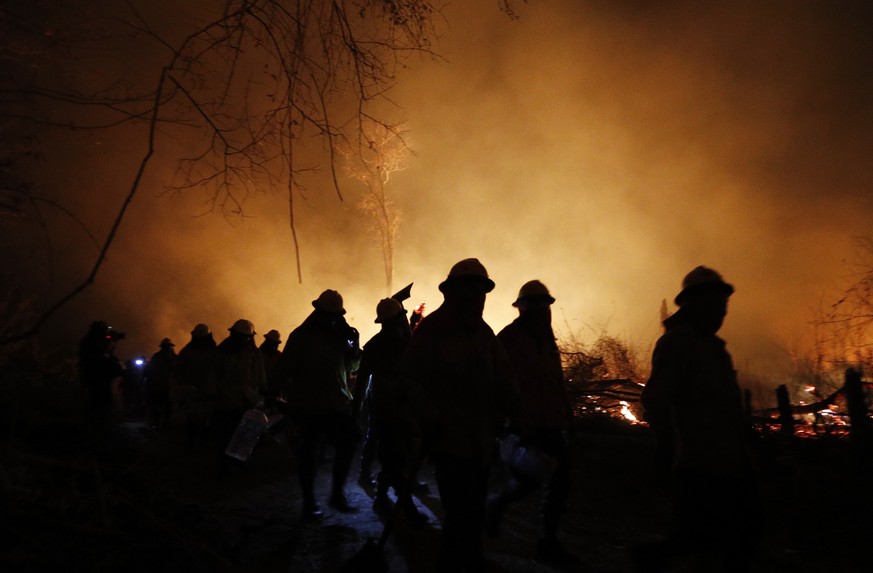 Marines are silhouetted against a raging fire in the Chiquitania Forest in Santa Rosa de Tucabaca, on the outskirts of Robore, Bolivia, Wednesday, Aug. 28, 2019. While some of the fires are burning in ...