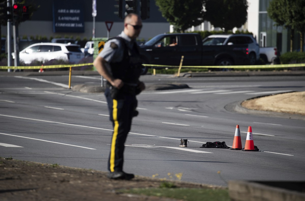 An RCMP officer stands near a shoe with blood on it and other belongings on the road at the scene of a shooting in Langley, British Columbia, Monday, July 25, 2022. Canadian police reported multiple s ...