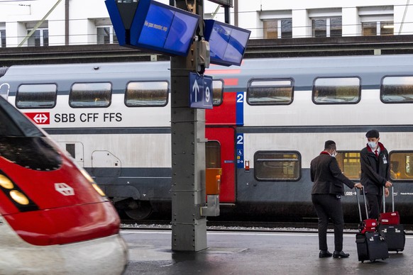 epa08415059 Two employees of the railway compagny CFF/SBB wait for a train at the train CFF/SBB station during the spread of the pandemic Coronavirus (COVID-19) disease in Lausanne, Switzerland, Monda ...