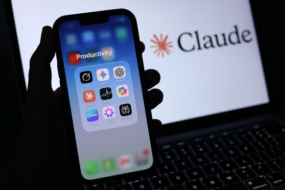 epa13026210 A 'Productivity' folder containing Artificial Intelligence applications is displayed on a mobile phone alongside the Anthropic Claude logo displayed on a laptop screen in Liverpo ...