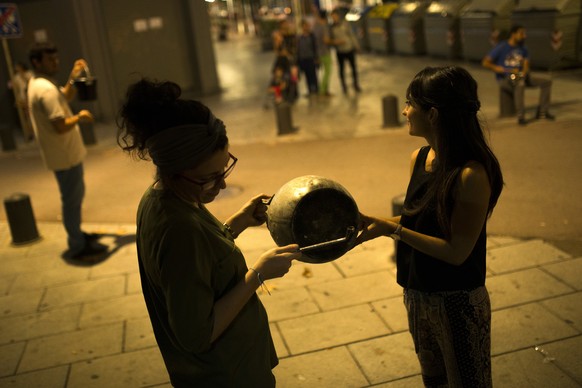 Zwei Demonstrantinnen hauen mit Stöcken auf einen Topf in Katalonien.