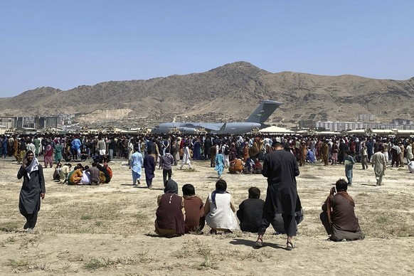 FILE - In this Aug. 16, 2021, file photo, hundreds of people gather near a U.S. Air Force C-17 transport plane along the perimeter at the international airport in Kabul, Afghanistan. In the U.S. depar ...