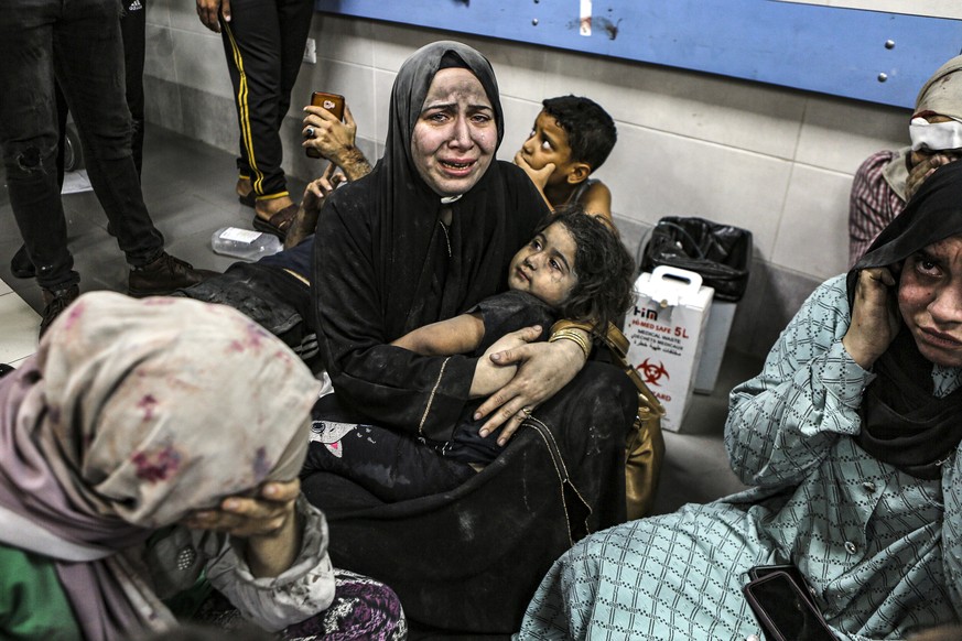 Palestinians wounded at Ahli Arab hospital sit on the floor at al-Shifa hospital, in Gaza City, central Gaza Strip, Tuesday, Oct. 17, 2023. The Hamas-run Health Ministry says an Israeli airstrike caus ...