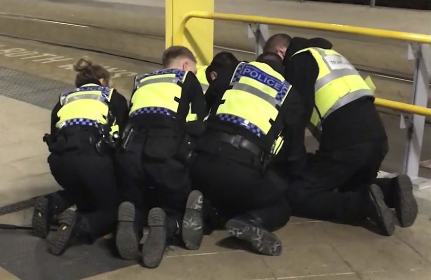 UGC issued by PA shows Police restraining a man after he stabbed three people at Victoria Station in Manchester, England, late Monday Dec. 31, 2018. Two commuters - a man and woman in their 50s - were ...