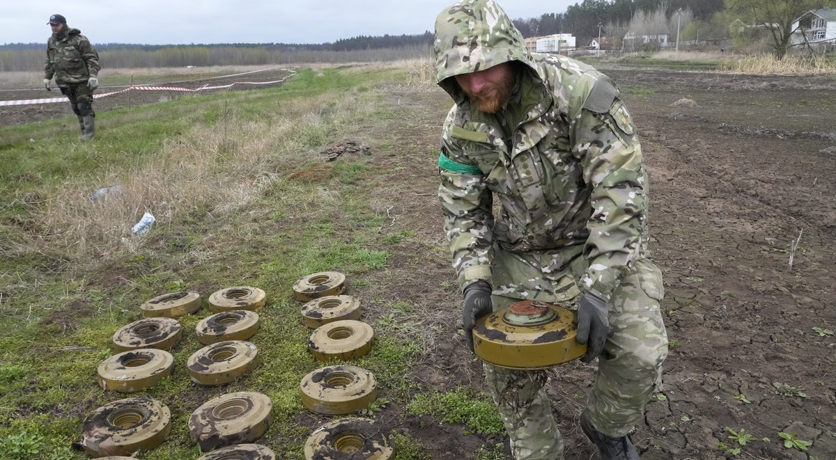 An interior ministry sapper collects mines on a mine field after recent battles in Irpin close to Kyiv, Ukraine, Tuesday, April 19, 2022. (AP Photo/Efrem Lukatsky)
