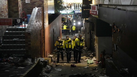 Police officers inspect the scene where people died and were injured in Seoul, South Korea, Sunday, Oct. 30, 2022, after a mass of mostly young people celebrating Halloween festivities in Seoul became ...