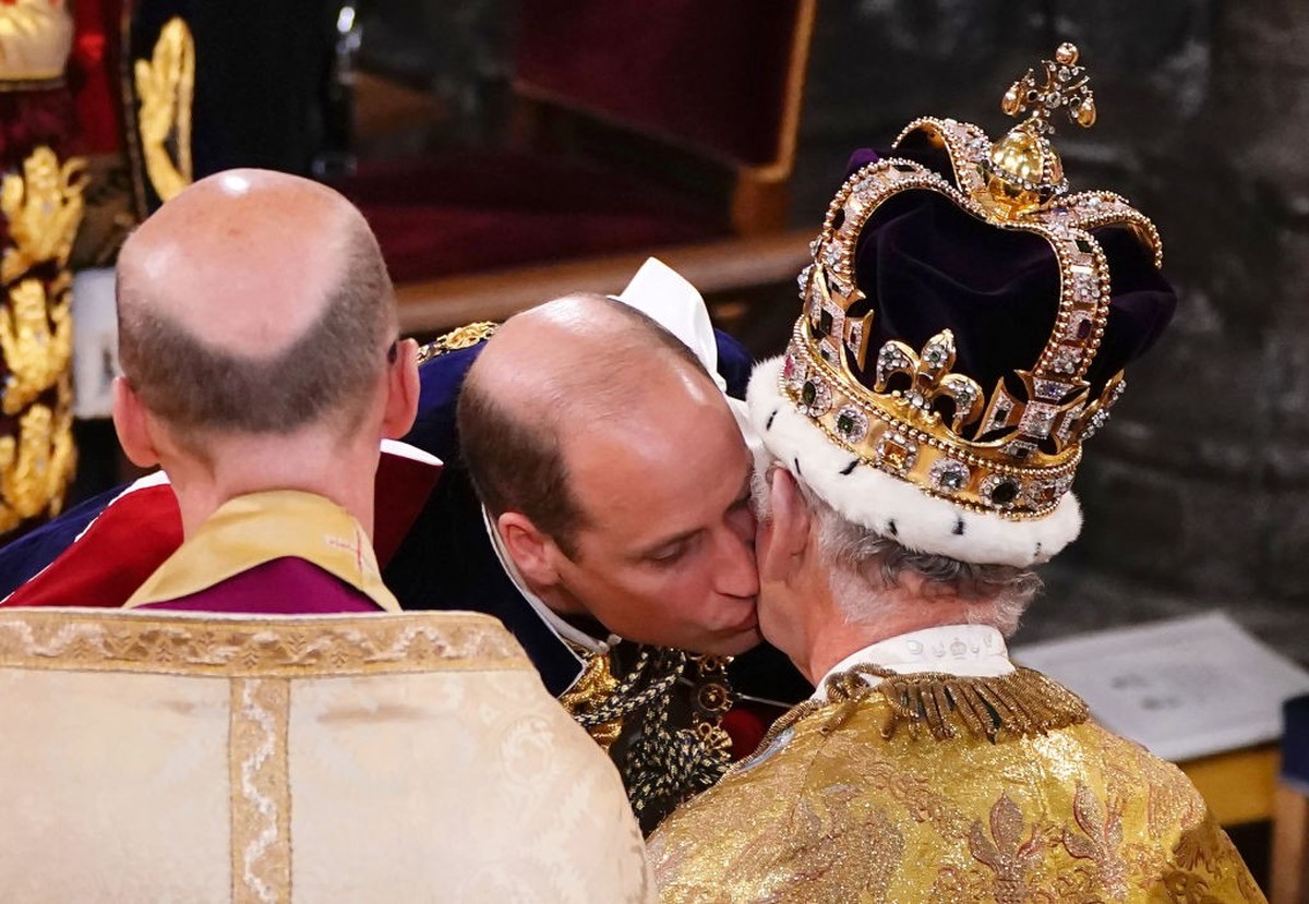 LONDON, ENGLAND - MAY 06: Prince William, Prince of Wales kisses his father, King Charles III, wearing St Edward's Crown, during the King's Coronation Ceremony inside Westminster Abbey on Ma ...