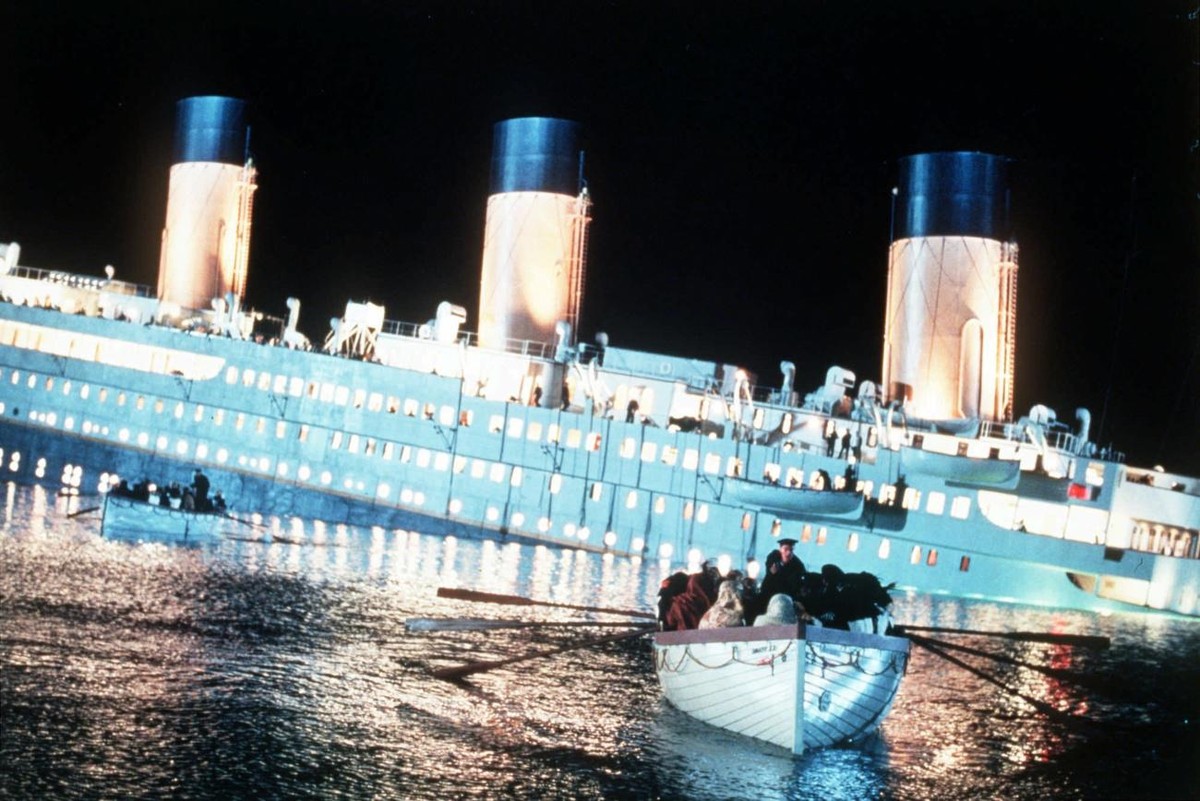 Actors and actresses portraying passengers of the Titanic row to safety aboard a lifeboat as the ill-fated ship sinks into the ocean in this scene from the movie "Titanic." Opening Dec. 19,  ...