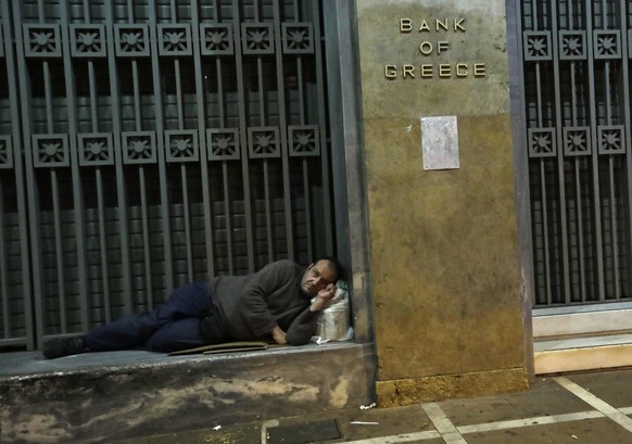 A homeless man rests on the steps of a branch of the Bank of Greece as demonstrators protested against the visit of US President Barack Obama in Athens, Tuesday, Nov. 15, 2016. Obama is in Athens for  ...