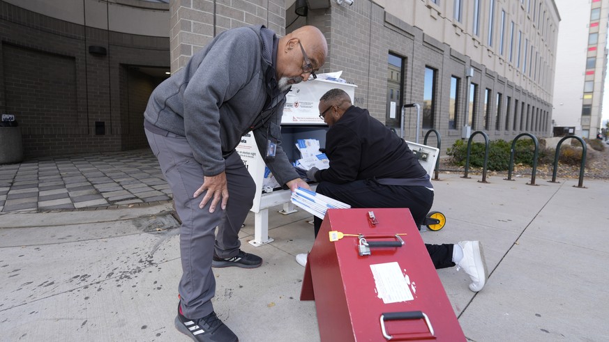 Denver Elections Division workers place ballots in collection box as they empty a drop box outside the headquarters early Tuesday, Nov. 8, 2022, in downtown Denver. (AP Photo/David Zalubowski)