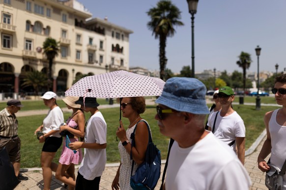 epa10745711 Thessaloniki residents and tourists with umbrellas from the high temperatures and the sun, Thessaloniki, Greece, 14 July 2023. Extremely high temperatures with a potentially serious impact ...