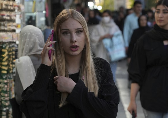 A woman talks on her cellphone as she walks around Tajrish commercial district without wearing the mandatory Islamic headscarf in northern Tehran, Iran, Saturday, April 29, 2023. More women are choosi ...