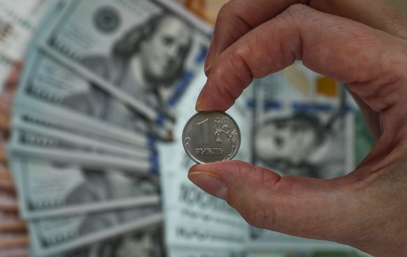 epa09900393 A photo illustration shows Russian ruble coin with euro and US dollar banknotes in Moscow, Russia, 21 April 2022. The Russian ruble continues to strengthen against other currencies and has ...