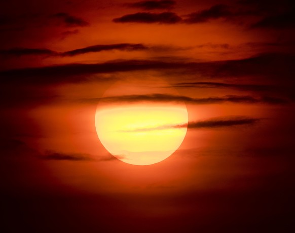 The setting sun is covered with clouds in Frankfurt, Germany, late Thursday, July 5, 2018. (AP Photo/Michael Probst)