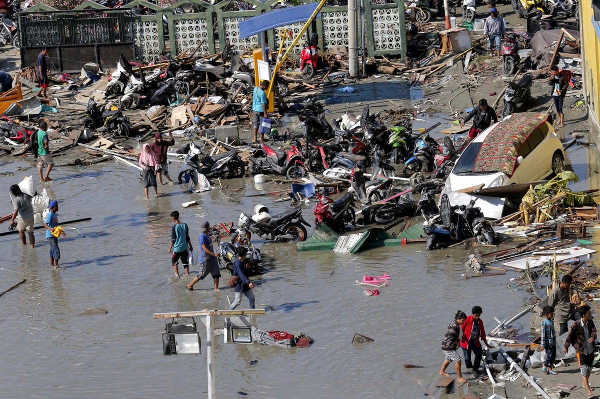 People survey outside the shopping mall which was damaged following earthquakes and a tsunami in Palu, Central Sulawesi, Indonesia, Sunday, Sept. 30, 2018. Rescuers try to reach trapped victims in col ...