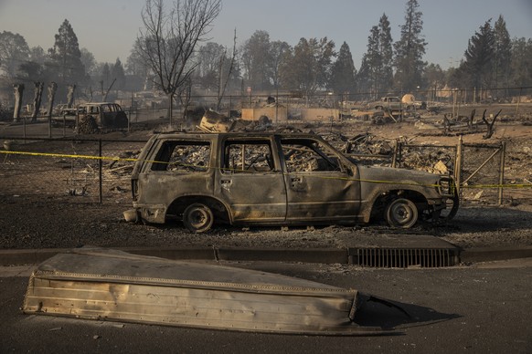 A boat is seen on a road in front of a burned vehicle in the Lincoln Heights neighborhood during the Mill Fire in Weed, Calif., Saturday, Sept. 3, 2022. (Stephen Lam/San Francisco Chronicle via AP)