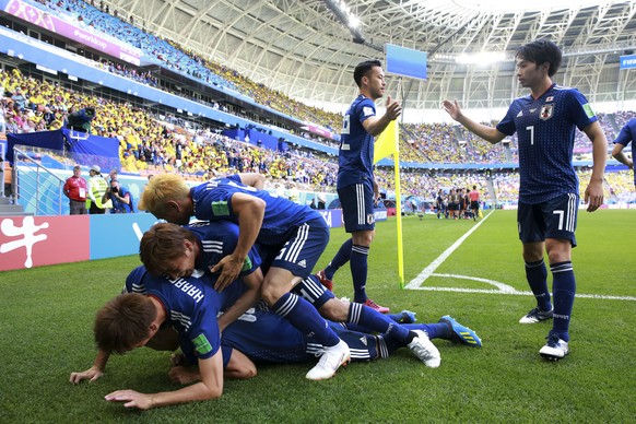 Teammates crowd over Japan&#039;s Shinji Kagawa after he scored from the penalty spot his side&#039;s first goal against Colombia during a group H match at the 2018 soccer World Cup in the Mordavia Ar ...