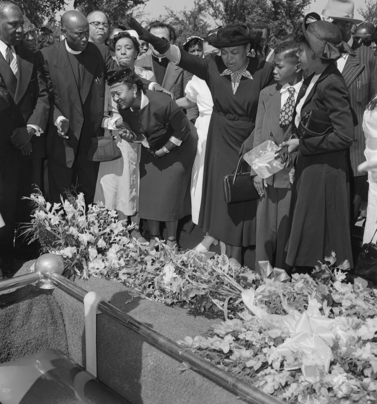 (Original Caption) Friends restrain grief-stricken Mrs. Mamie Bradley (left) as her son's body is lowered into the grave after a four day, open casket funeral. The 15-year old Negro youngster, Em ...