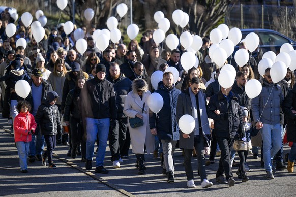 People carry white balloons as they take part of a &quot;Marche Blanche&quot; (White March) to pay tribute for the victims of the 11 December shooting, in Sion, Switzerland, Saturday, December 16, 202 ...