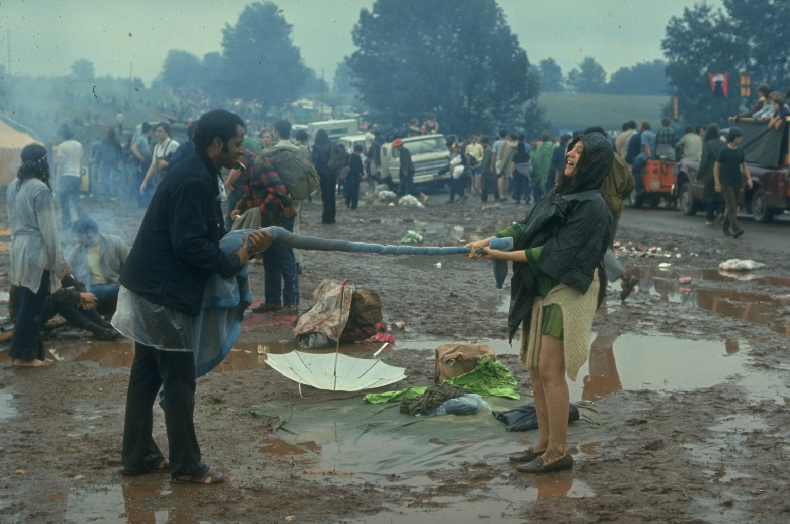 NEW YORK, UNITED STATES - AUGUST 1969: Couple twisting a blanket between them, probably trying to squeeze out the water, during the Woodstock Music & Art Fair. (Photo by John Dominis/The LIFE Pict ...