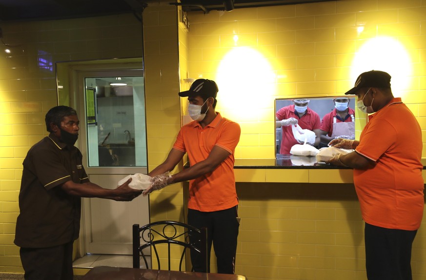 Taj al-Islam, 50 year old Bangladeshi carwash worker, 1st left, receives his free food at a restaurant in Sharjah, United Arab Emirates, Wednesday, Nov. 4, 2020. In this industrial underbelly in the s ...