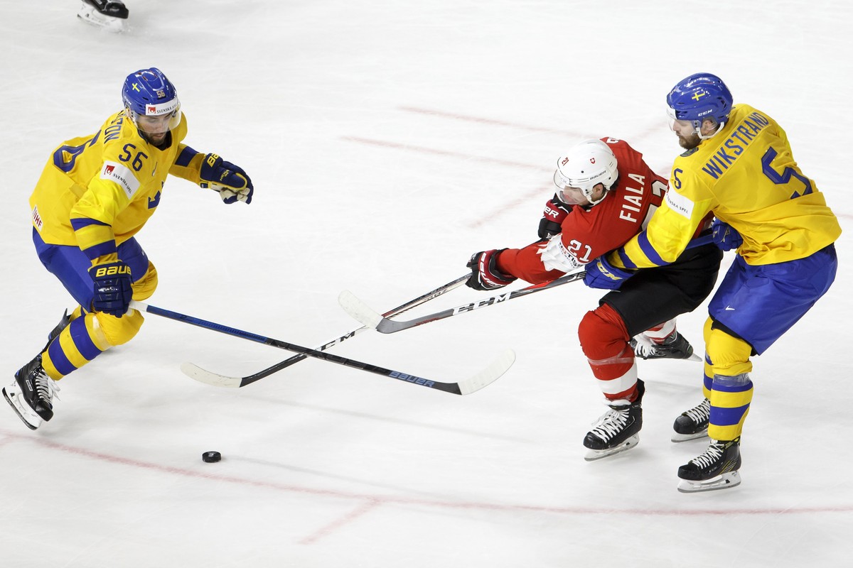 epa06734039 Switzerland's forward Kevin Fiala, center, vies for the puck with Sweden's players defender Erik Gustafsson, left, and defender Mikael Wikstrand, right, during the IIHF 2018 Worl ...