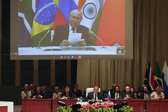 Russia&#039;s Foreign Minister Sergei Lavrov, centre, listens during the plenary session as Russian President Vladimir Putin delivers his remarks via video link, during the 2023 BRICS Summit in Johann ...