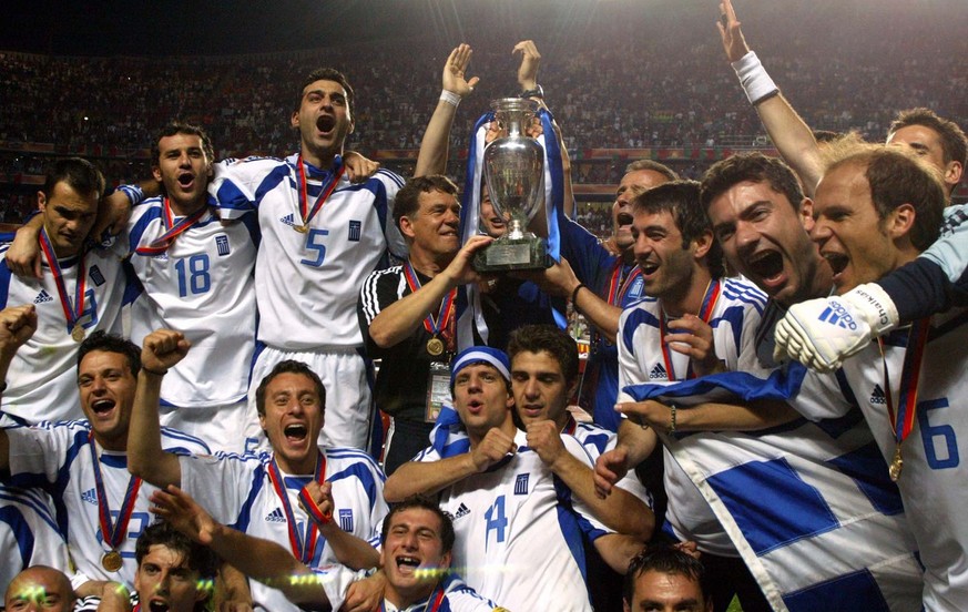 Greece&#039;s coach Otto Rehhagel holds the trophy as he celebrates with his players after beating Portugal, 1-0, in the Euro 2004 soccer championship final match, at the Luz stadium in Lisbon, Portug ...