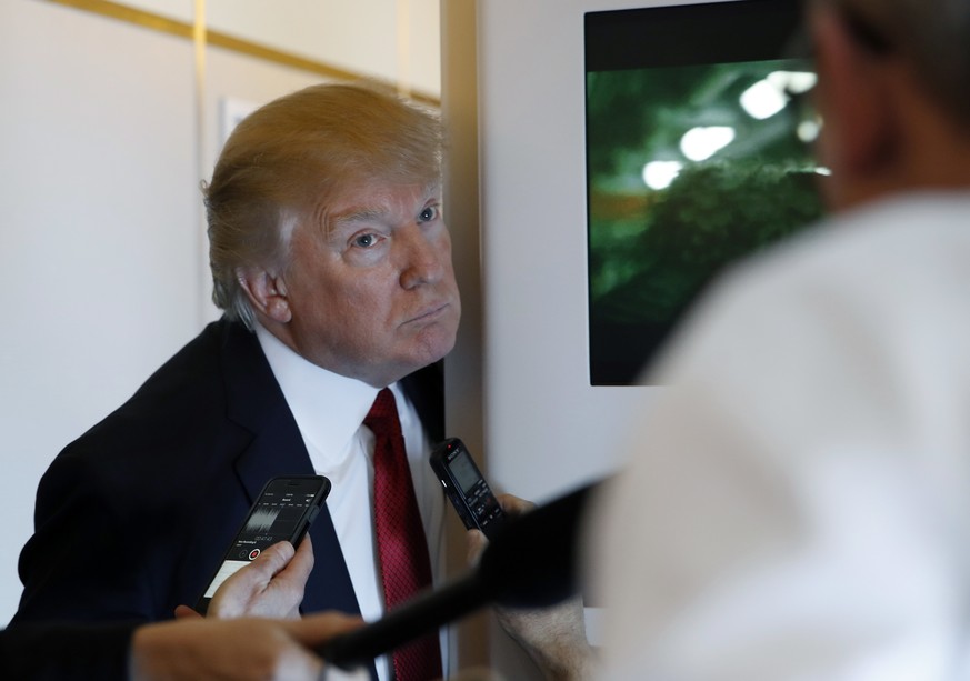 President Donald Trump speaks with reporters on Air Force One while in flight from Andrews Air Force Base, Md., to Palm Beach International Airport, Fla., Thursday, April 6, 2017. (AP Photo/Alex Brand ...