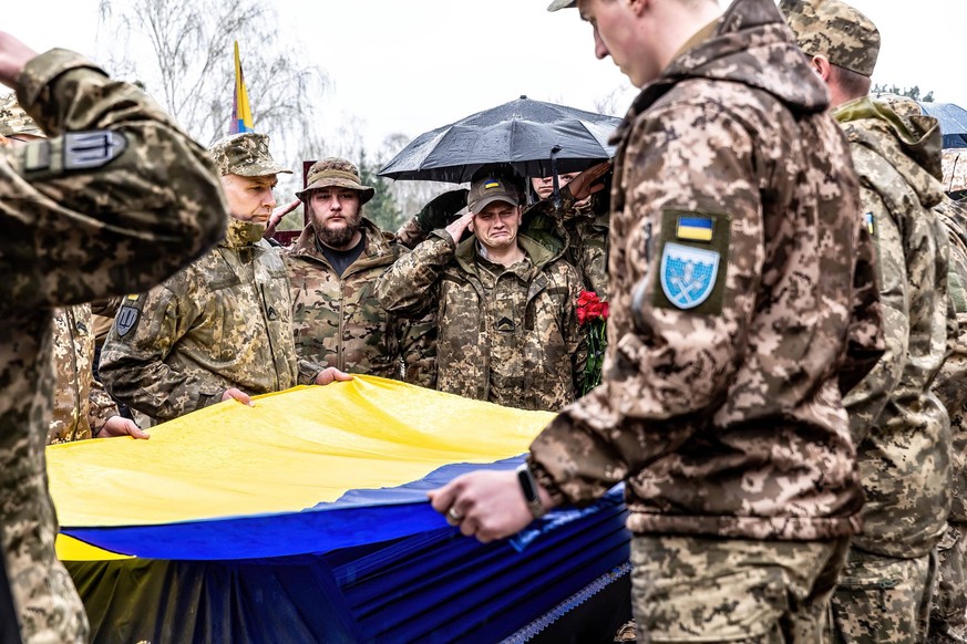 April 12, 2023, Kyiv, Ukraine: Servicemen hold Ukrainian flag by the coffin during the funeral of Evgeny Yakovlev, 42, a soldier killed by Russian forces on eastern Ukrainian front in a combat, at the ...
