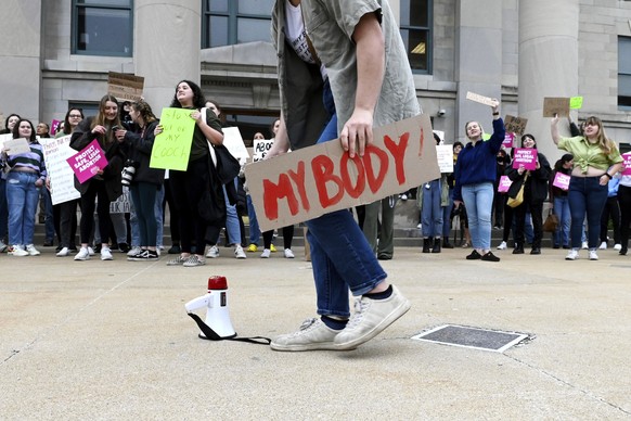 Shayna Crosby leans down to grab a megaphone before speaking to a crowd of abortion rights supporters outside the Boone County Courthouse in Columbia, Mo., Tuesday, May 3, 2022, in response to the new ...