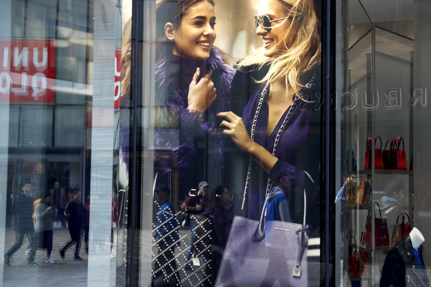 Shoppers are reflected on a fashion boutique window as they walk through the capital city&#039;s popular shopping mall in Beijing, Thursday, Oct. 19, 2017. China&#039;s economic growth edged down in t ...