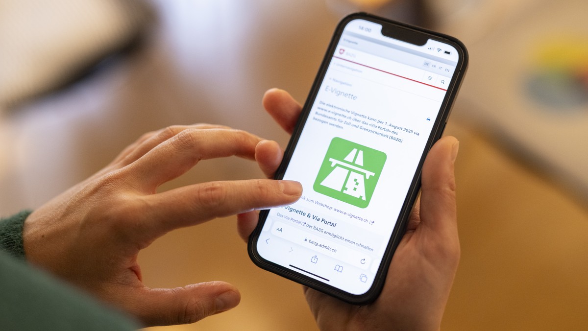 Eine Frau loest eine elektronische Vignette, die E-Vignette, zur Nutzung von abgabepflichtigen Autobahnen und Autostrassen fuer das Jahr 2024 auf ihrem Telefon, aufgenommen am Freitag, 1. Dezember 202 ...