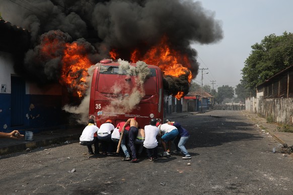 Demonstrators push a bus that was torched during clashes with the Bolivarian National Guard in Urena, Venezuela, near the border with Colombia, Saturday, Feb. 23, 2019. Venezuela&#039;s National Guard ...