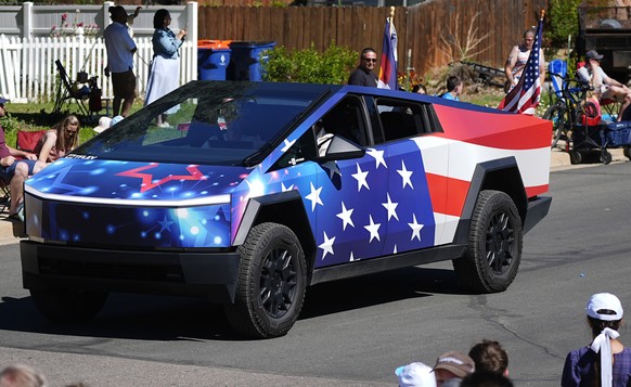 FILE - A Tesla Cybertruck wrapped in patriotic motif rolls along in the Colorado 4th at Firestone parade to mark the Independence Day holiday July 4, 2024, in Firestone, Colo. Tesla reports earnings o ...