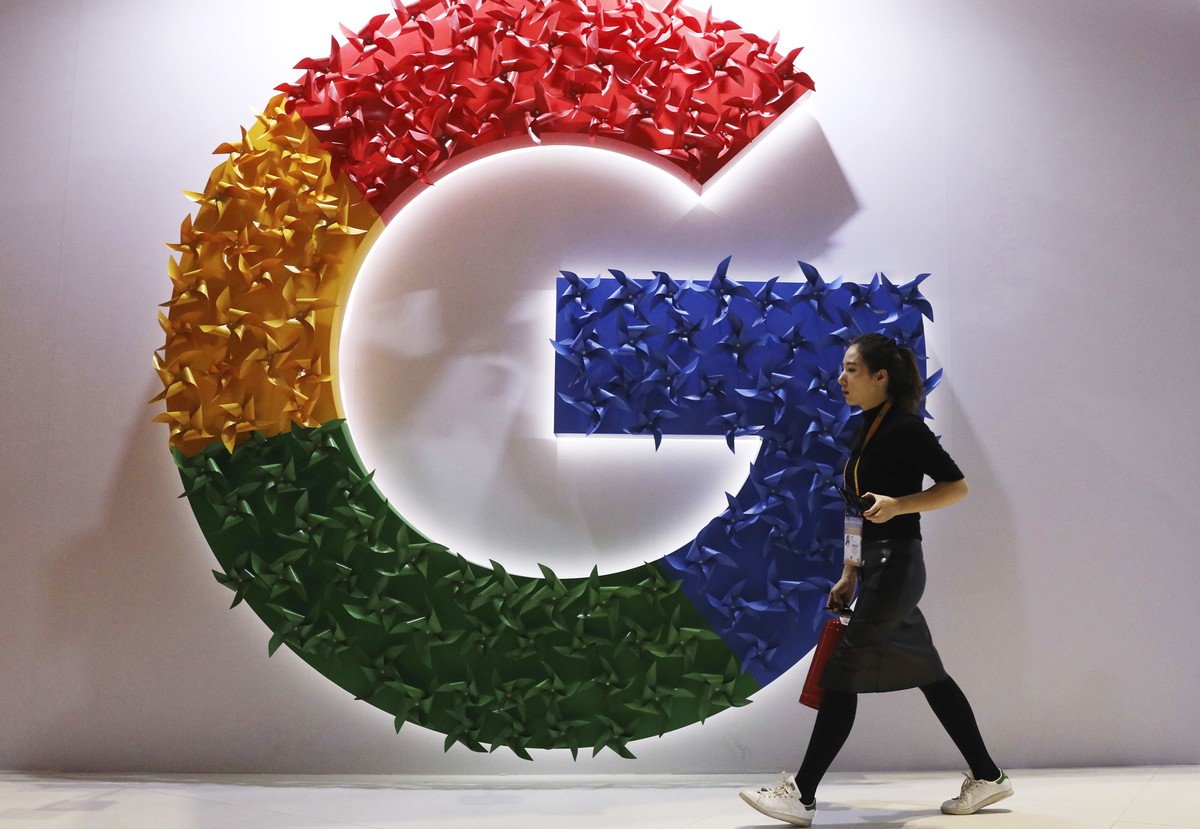 FILE - In this Nov. 5, 2018 file photo, a woman walks past the logo for Google at the China International Import Expo in Shanghai. Google is dropping plans to eliminate cookies from its Chrome web bro ...