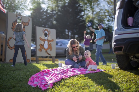 epa08384473 The Queen family, including mother LaTasha (C-L) and her 8-month-old daughter Kaci, relax after arriving early for a double feature movie Tiger Drive-In theater in the tiny mountain town o ...