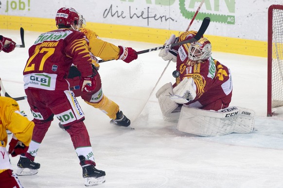 Langnaus Torhueter Damiano Ciaccio, rechts, stoppt den Puck, an der Seite von Biels Julian Schmutz, mitte, und Langnaus Anthony Huguenin, links, beim Eishockey Meisterschaftsspiel der National League  ...