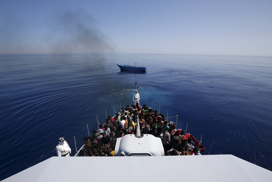 Gerettete Flüchtlinge, dahinter ihr Boot.