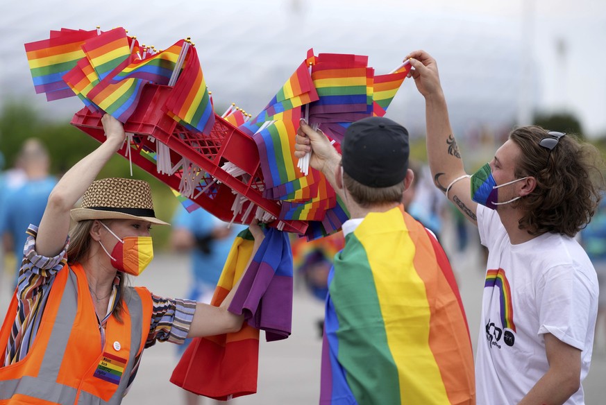 A woman offers LGBT pride flags to football supporters outside of the stadium before the Euro 2020 soccer championship group F match between Germany and Hungary at the Allianz Arena in Munich, Germany ...