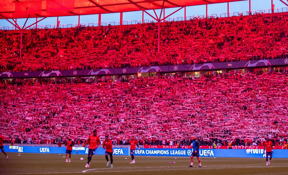 03.10.2023, Berlin: Fu�ball: Champions League, 1. FC Union Berlin - SC Braga, Gruppenphase, Gruppe C, 2. Spieltag, An der Alten F�rsterei. Fans von Union Berlin feuern ihr Team mit Schals im rot beleu ...