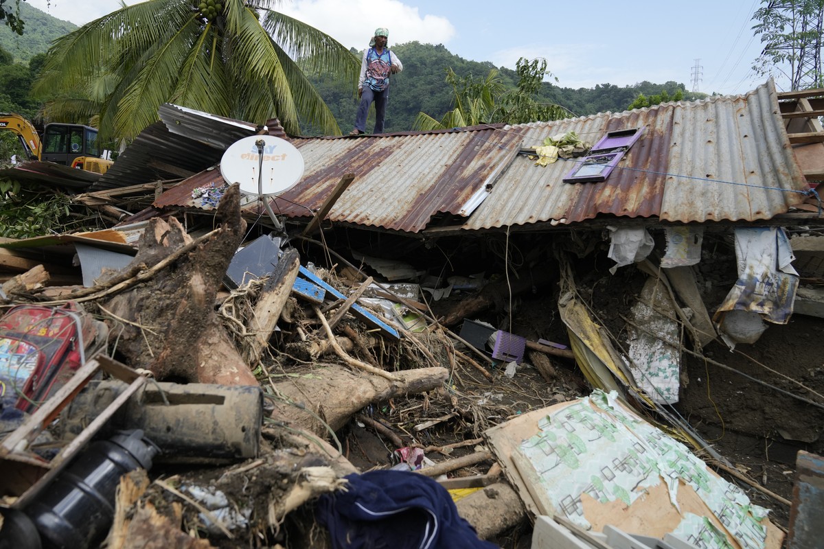 Marcelino Aringo stands on top of a damaged house after a landslide triggered by Tropical Storm Trami recently struck Talisay, Batangas province, Philippines, Saturday, Oct. 26, 2024 . (AP Photo/Aaron ...